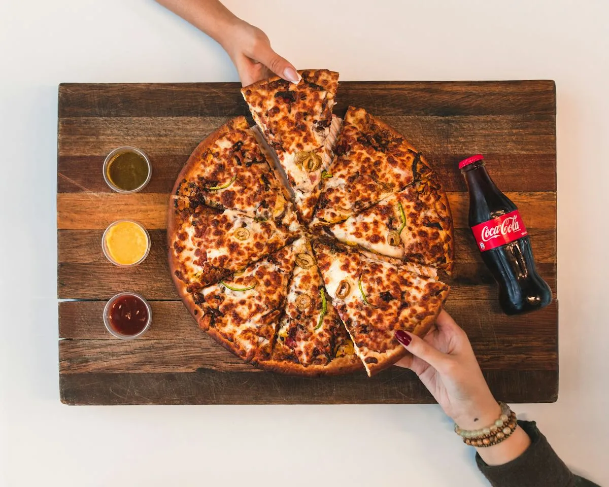 Guests sharing slices of pizza at a rustic wooden table