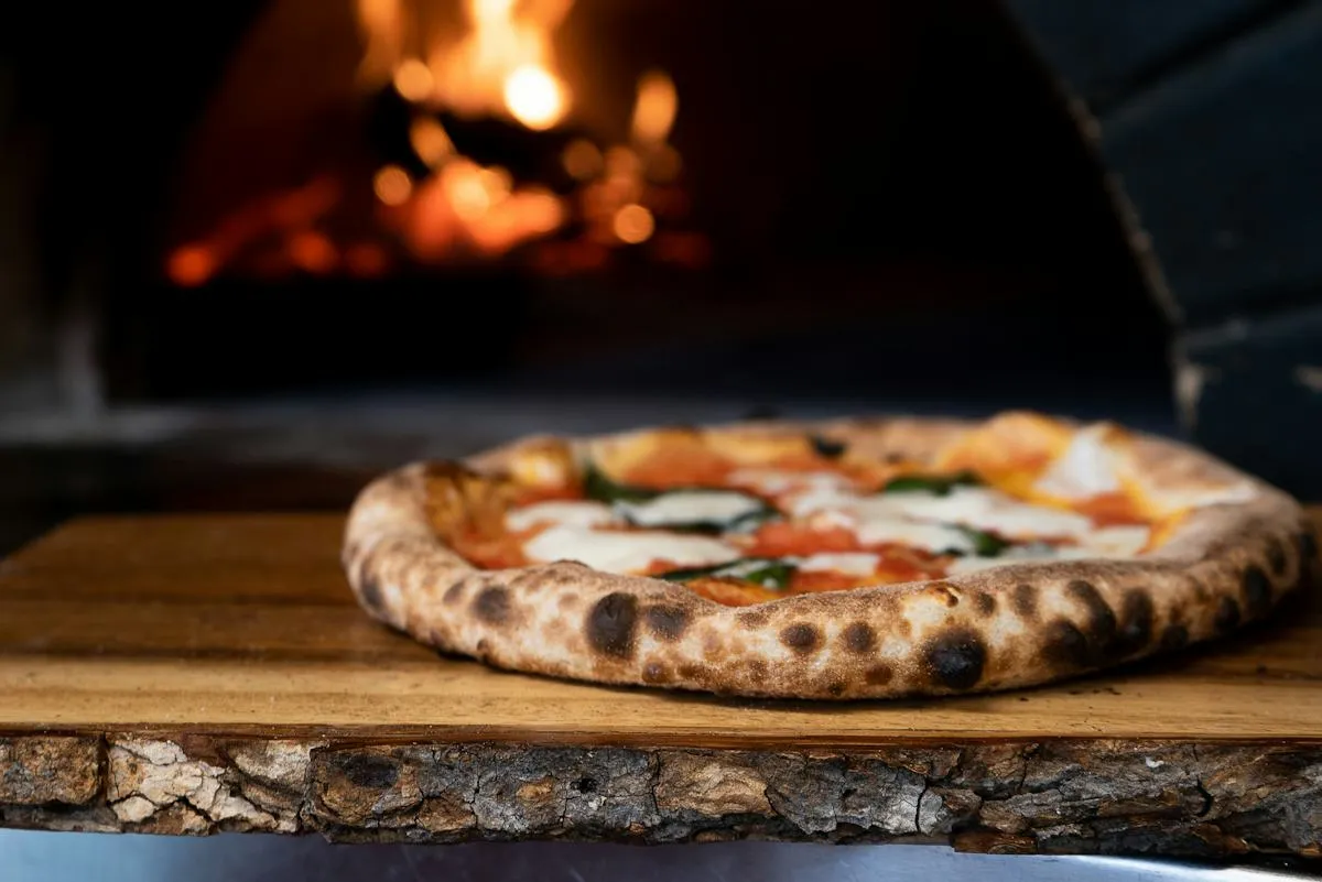 Handmade Margherita pizza by a glowing wood-fired oven