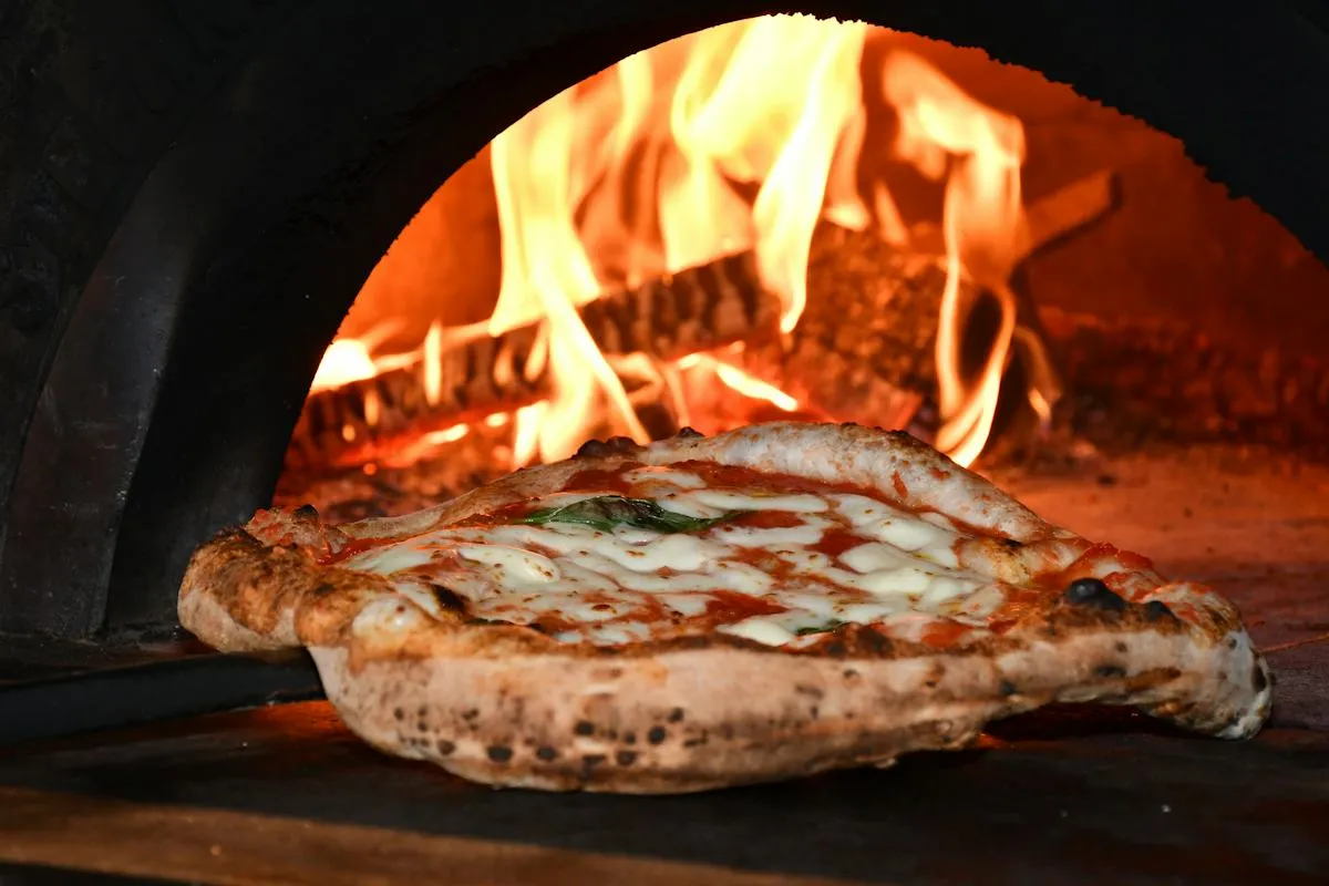 Freshly baked pizza emerging from a traditional oven