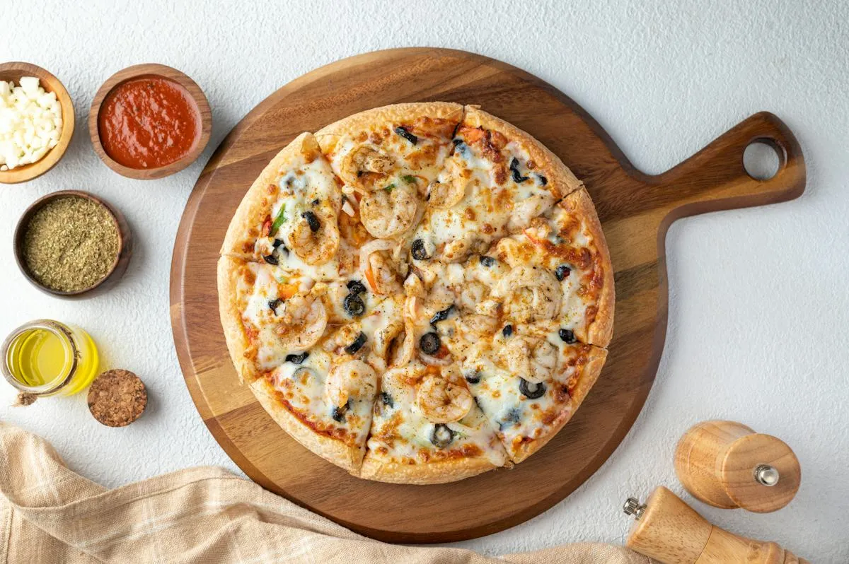 Italian-style pizza on a wooden serving board with small bowls of seasoning