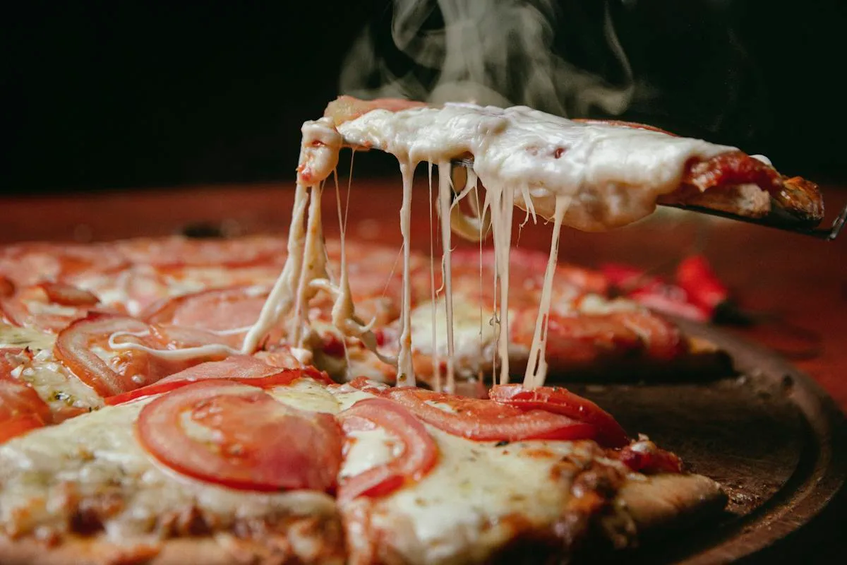 Hot cheese pizza with a slice being lifted